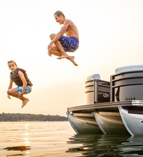 Two people jumping off of a Barletta pontoon