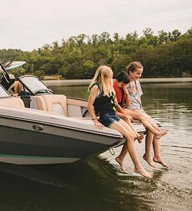 Three people on the bow of a Mastercraft boat