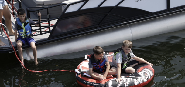 Kids on a tube with a pontoon boat