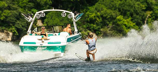 Girl wakeboarding with a green Tige boat