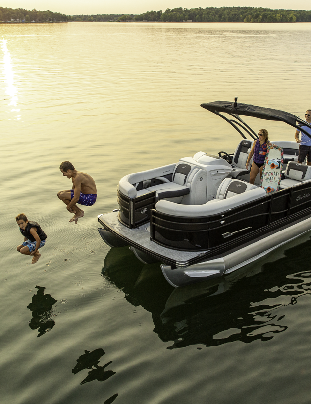 Two kids jumping off of a pontoon boat